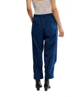 Pantalón de vestir azul con rayas verticales finas en color marrón claro. Diseño de tiro alto con elástico en la cintura y pliegues marcados en la parte delantera de las piernas. El corte es relajado y el largo es al tobillo.