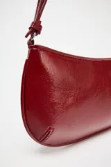Bolso de hombro color rojo con efecto craquelado, asa corta y cierre de cremallera.