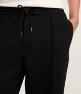 Pantalón de vestir negro, de corte recto, con cintura elástica ajustable con cordón, trabillas para cinturón, cierre de botón y cremallera, y bolsillos laterales. Confeccionado en poliéster, viscosa y elastano.