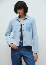 Campera de jean celeste claro, corte crop, con cuello clásico, cierre frontal con botones, mangas largas, dos bolsillos frontales y ruedo desflecado.