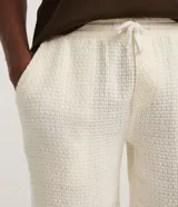 Bermuda de hombre color blanco crudo, confeccionada en algodón texturizado. Presenta un corte comfort, cintura elástica con lazo ajustable y bolsillos laterales.