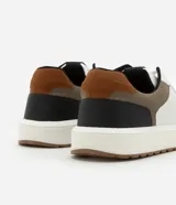 Championes casuales de material sintético color blanco con recortes en marrón, negro y beige. Presentan puntera redonda, cordones y suela contrastante color caramelo.