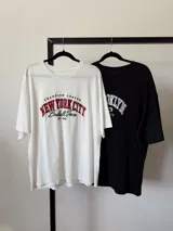 Remera oversize blanca con estampado frontal que dice "Champion League New York City Baseball Team Est. 1985" en rojo y negro.