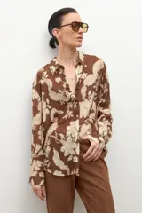 Camisa de manga larga con cuello y botones frontales, confeccionada en tela ligera con estampado floral en tonos marrón chocolate y beige claro.