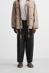Pantalón de lino color marrón oscuro, de corte recto y relaxed fit. Tiene cintura elástica ajustable con cordón, bolsillos frontales y traseros de parche.