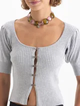 Top corto gris de punto acanalado, con escote redondo, manga corta abullonada y cierre frontal con tres ganchos decorados con piedras.