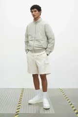 Short cargo color crema en popelina de algodón, con cintura elástica ajustable con cordón, bolsillos laterales y bolsillos con solapa y botones a presión en las piernas y atrás.