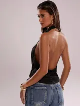 Top corto negro con cuello drapeado, espalda descubierta y tirantes finos.