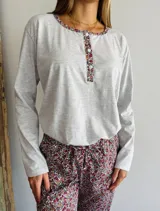 Conjunto de pijama gris melange con estampado floral, compuesto por una remera de manga larga con cuello redondo y botones, y un pantalón largo con cintura elástica y lazo ajustable.