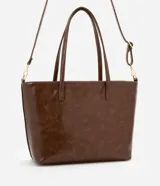 Bolso shopper grande color marrón de material sintético con doble asa, una fija y otra larga desmontable. Tiene cierre de cremallera y detalles de recortes.