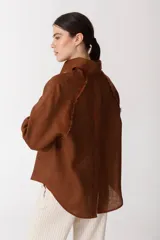 Camisa blanca de lino con botones de madera, corte recto y mangas largas.