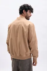 Campera estilo bomber de hombre, color tostado, con cierre frontal metálico, cuello y puños acanalados.