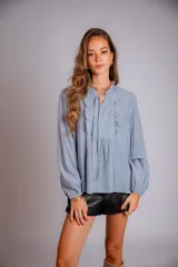 Camisa celeste con volados en cuello y en la parte delantera, con cordones.