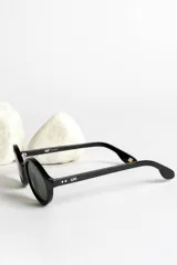 Lentes de sol con montura redonda negra y cristales verdes.