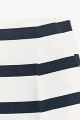 Bermuda de tiro alto a rayas horizontales blancas y azul marino, con pinzas delanteras, bolsillos frontales y cierre delantero con cremallera, botón interior y gancho.