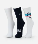 Kit de tres pares de medias Puma de caña alta, confeccionadas en algodón más sostenible. Incluye un par blanco con logo rojo, un par azul marino con logo blanco y texto, y un par blanco con logo y diseño deportivo en azul y rojo.