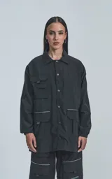 Campera negra oversize con broches en el delantero, forrada con red, múltiples bolsillos con detalles réflex y puños elásticos.