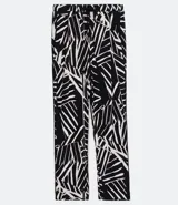 Pantalón pijama fluido de viscosa con estampa geométrica en blanco y negro. Tiene cintura media con ajuste de cordón con puntera metálica, bolsillos y prega frontal.
