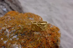 Anillo plateado con textura irregular y diseño rústico.