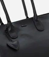 Bolso shopper grande de cuero sintético negro con asas medianas y cierre de cremallera. Incluye un dije colgante en forma de corazón y una pequeña cartera extra.