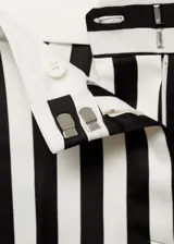 Pantalón largo de tela fluida con estampado de rayas verticales en blanco y negro. Diseño recto con bajo con vuelta, cierre oculto de botón, gancho y cremallera, y dos bolsillos laterales.