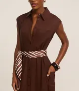 Vestido chemise de lino color negro, con cuello camisero, sin mangas y cierre frontal con botones. Incluye cinturón de tela estampado.