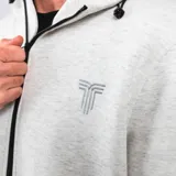 Canguro gris con cierre frontal, capucha con cordones ajustables, bolsillos laterales con ribete negro y logo estampado en el pecho.