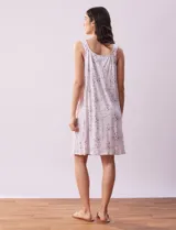 Camisón corto de tejido suave con estampado de rosas rosadas sobre fondo lila. Tiene escote redondo con detalle de puntilla blanca y botones.