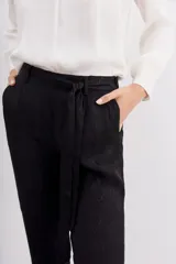 Pantalón sastrero negro, corte al tobillo, confeccionado en jacquard con un patrón sutil. Presenta presillas y un lazo de ajuste en la cintura elastizada.