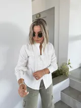 Camisa blanca de corte clásico con detalles de encaje en el frente y mangas largas con puños abotonados.