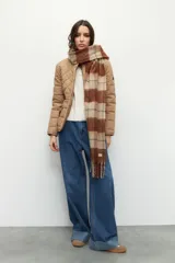 Campera capitoneada color beige, de cuello alto, con bolsillos de solapa y botones metálicos.
