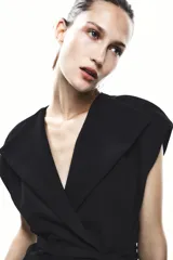 Chaleco negro cruzado con cuello solapa y sin mangas. Incluye cinturón de la misma tela para ajustar a la cintura.