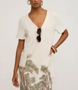 Vestido t-shirt corto de viscolino color crudo, con escote en V y manga corta. Presenta un estampado de follaje en tonos verdes y rosados en el bajo.