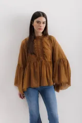 Camisa color marrón con cuello mao, mangas largas abullonadas y detalle de volados en el frente.