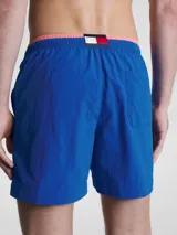 Bañador azul eléctrico de largo medio, con cintura elástica ajustable con cordón, ribete naranja en la cintura y logo de Tommy Hilfiger bordado en la parte trasera.