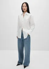 Camisa blanca de popelina de algodón y lyocell, con bordado floral en el frente, corte oversize, cuello camisero, mangas largas con puños abotonados y cierre frontal con botones.