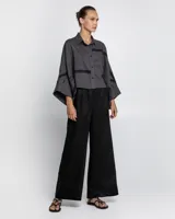 Camisa gris con bordados negros, de corte holgado y mangas anchas.