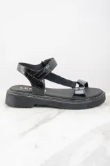 Sandalias negras de cuero con plataforma y tiras ajustables.