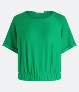 Blusa cropped verde de malla flamé, con cuello redondo, manga corta con doblez y elástico en el bajo.