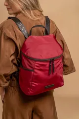 Mochila urbana de diseño compacto, color violeta/malva, con acabado ligeramente brillante. Presenta un compartimento principal con doble cierre superior y bolsillos laterales con cierre.