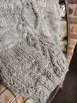 Chaleco tejido a mano color gris claro, con cuello en V y diseño trenzado.