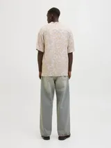 Camisa de manga corta color beige con estampado abstracto blanco, cuello resort, cierre con botones y corte relajado. Confeccionada en viscosa LENZING™ ECOVERO™.