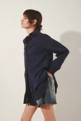 Camisa blanca de algodón con fit amplio, cuello y cartera frontal, y bordados calados en el frente, mangas y espalda. Posee tajos laterales y presillas internas para regular el largo de las mangas.