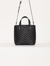 Cartera tote pequeña de cuero sintético negro con diseño acolchado en forma de espiga. Tiene doble asa corta superior, correa larga ajustable y desmontable, y logo metálico frontal con forma de labios.