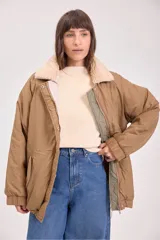 Campera acolchada reversible color verde militar, con capucha y cierre frontal con botones a presión.