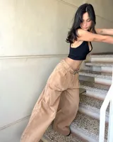 Pantalón de jean color beige, de corte ancho y tiro alto, con cinturón de cuero con hebilla metálica.