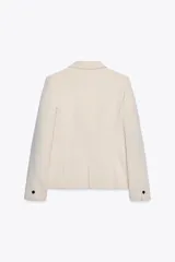 Blazer negra de corte clásico, con cuello solapa, manga larga, bolsillos frontales con solapa y cierre frontal con un botón.