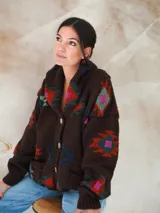 Saco de lana marrón con diseño geométrico multicolor, cuello con solapa, cierre frontal con botones y bolsillos delanteros.
