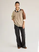 Buzo de punto con diseño texturizado en tonos beige y marrón, cuello con detalle negro y corte holgado.
