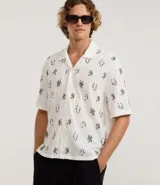 Camisa de manga corta para hombre, corte boxy, color blanco con cuello bowling y un estampado repetitivo de figuras geométricas negras.